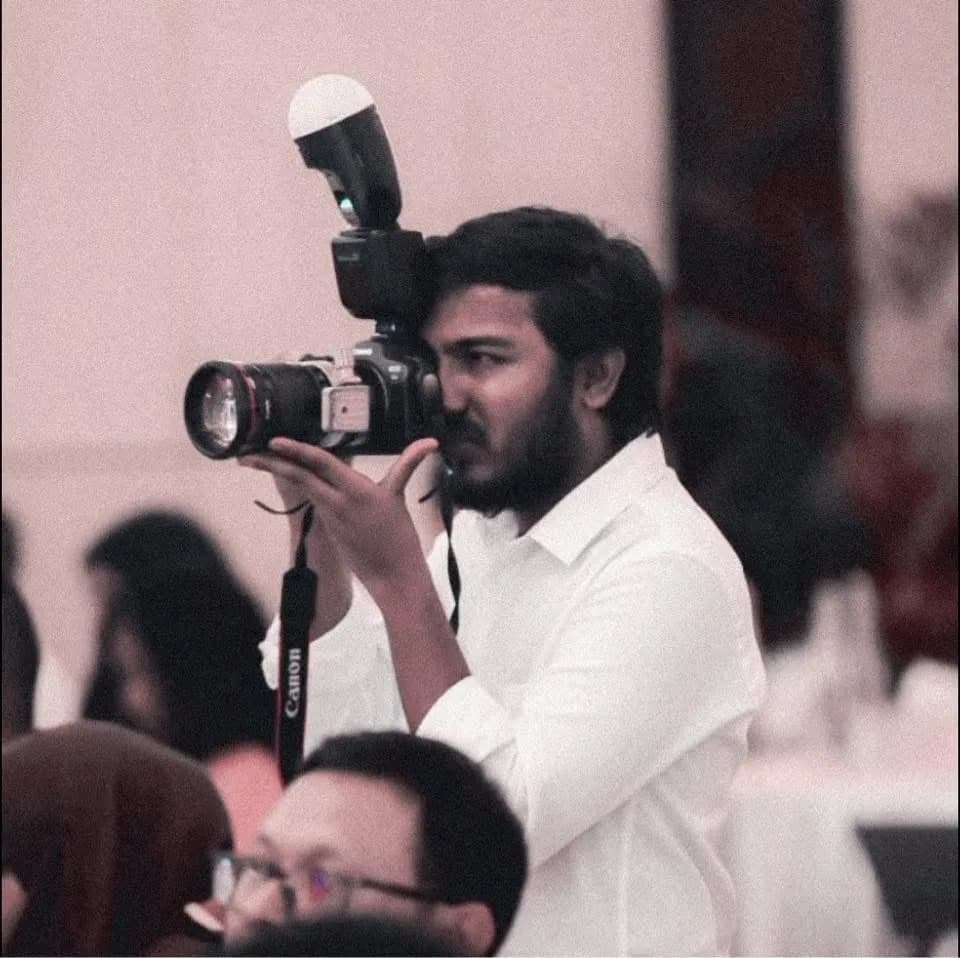 Ifaaz photographing an event, camera raised to his eye